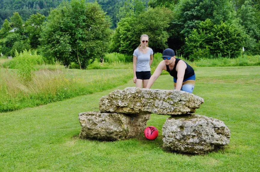 Zwei Erwachsene spielen den Ball durch ein Steinhindernis bei Kick2Gether