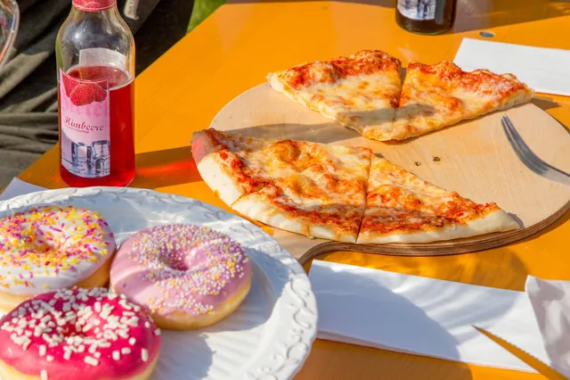 Pizza, süße Snacks und ein Getränk auf einem Tisch im Kick2Gether-Bistro