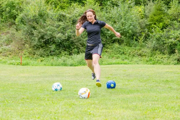 Ein junger Fußballgolf-Spieler beim Abschlag auf dem Rasen