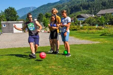 Drei Erwachsene stehen mit einem Fußball auf der Anlage zusammen