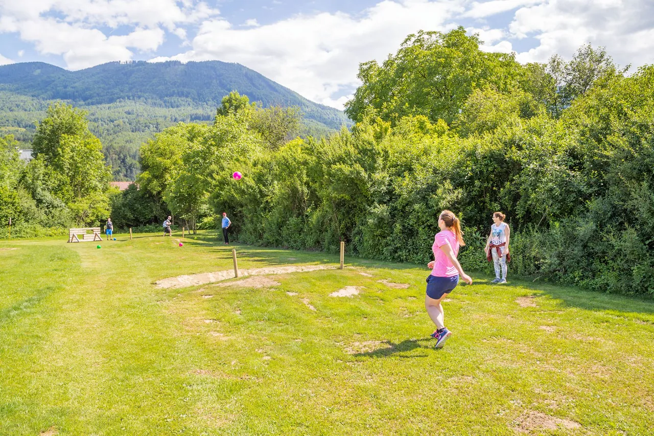 Eine Spielerin auf einer Fußballgolf-Bahn mit Bergpanorama im Rosental