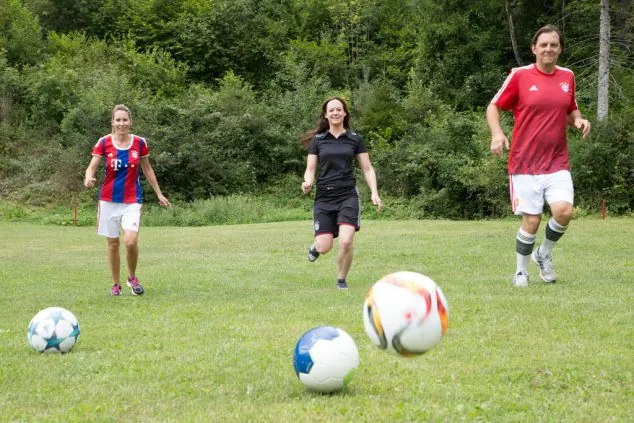 Drei junge Spieler üben ihre Kicks mit Fußbällen auf dem Rasen