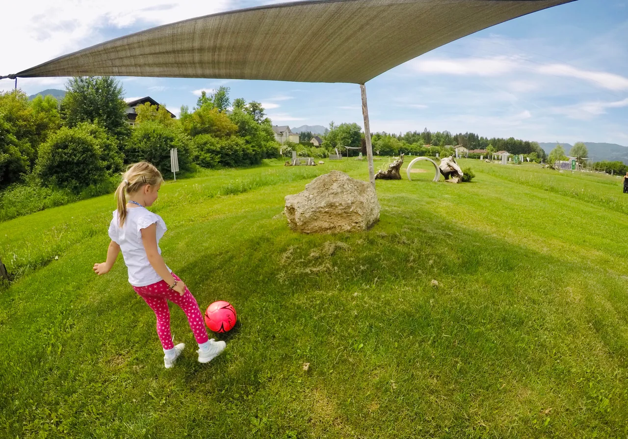 Ein Kind kickt einen pinken Fußball auf einer Bahn bei Kick2Gether